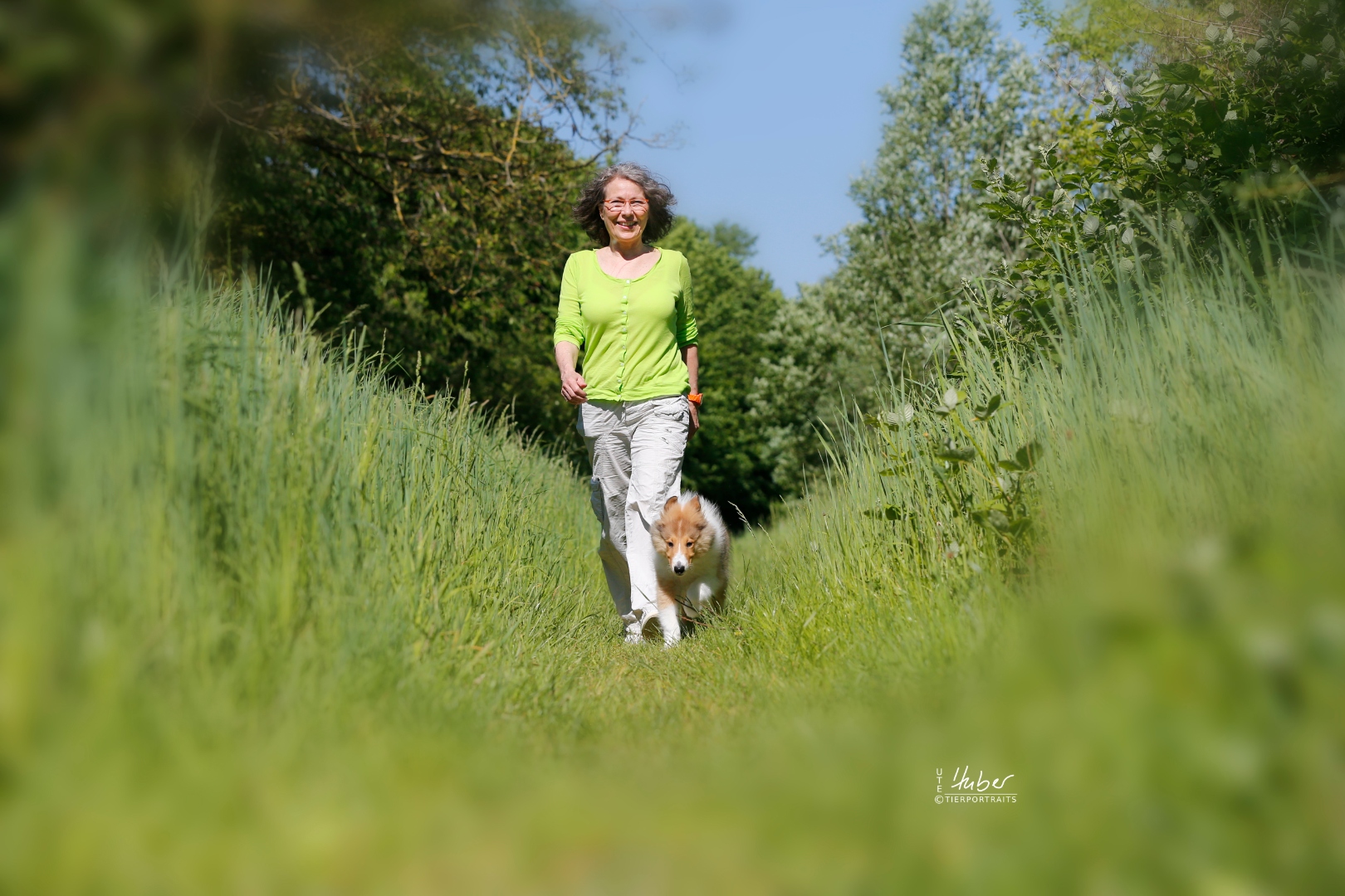 Andrea Kurz wandert mit ihrem Hund durch eine grüne Wiese